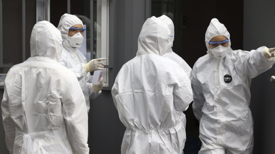 Officials wearing protective attire work to diagnose people with suspected symptoms of the virus in South Korea.