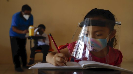 Wearing a mask and a face shield to curb the spread of the new coronavirus, 10-year-old Jade Chan Puc writes in her workbook during the first day of class at the ValentÃ­n Gomez Farias Indigenous Primary School in Montebello, Hecelchakan, Campeche state, Monday, April 19, 2021.