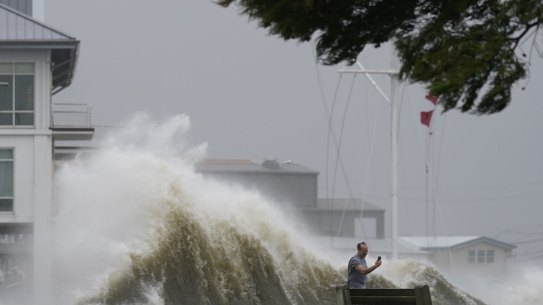 A man takes pictures of high waves along the shore of Lake Pontchartrain as Hurricane Ida nears, Sunday, Aug. 29, 2021, in New Orleans. (AP Photo/Gerald Herbert)