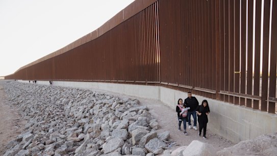 Migrants walk along the border fence before surrendering to US Border Patrol agents at the US-Mexico border in Yuma, Arizona, in May.
