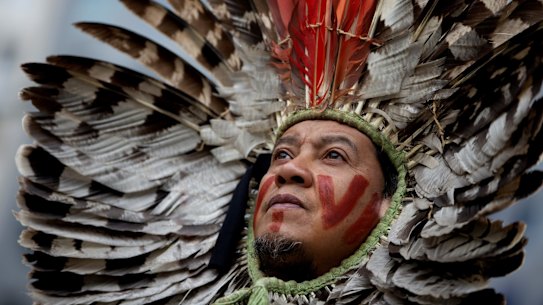 A leader of an indigenous community in Brazil wears a feather headdress as he protests forest destruction in Brussels last year.