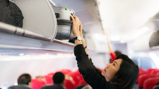 Traveler and tourism woman open overhead locker on airplane ,Hand-luggage compartment with suitcases in airplane. Hands take off hand luggage. Passenger put cabin bag cabin on the top shelf. Travel concept sunaug28betterÂ how to be a better traveller ; text by Lee Tullochcr:Â iStockÂ (reuse permitted, noÂ syndication)Â 