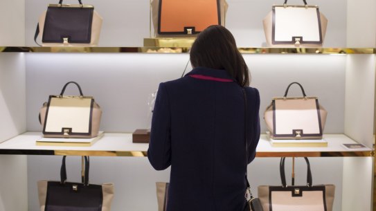 A shopper browses luxury leather handbags in Hong Kong.