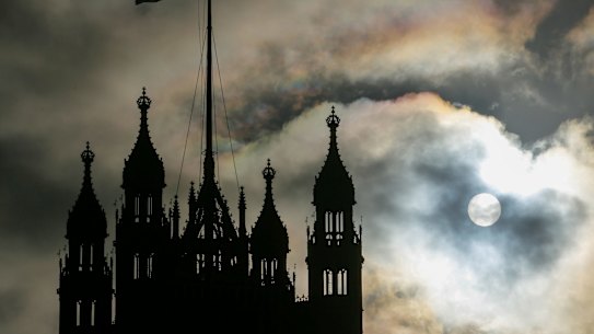 The sun breaks through clouds behind the Houses of Parliament in London.