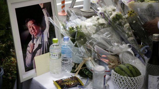 Flowers, bottles of water and a framed photograph of former Japanese prime minister Shinzo Abe rest in a makeshift shrine near the crime scene in Nara on Saturday.