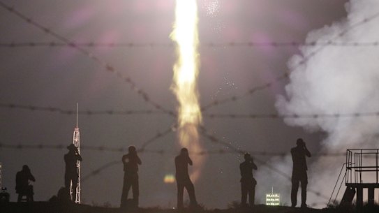 People watch a Soyuz-FG rocket booster carrying a new crew to the International Space Station blast off at the Russian leased Baikonur cosmodrome in Kazakhstan.
