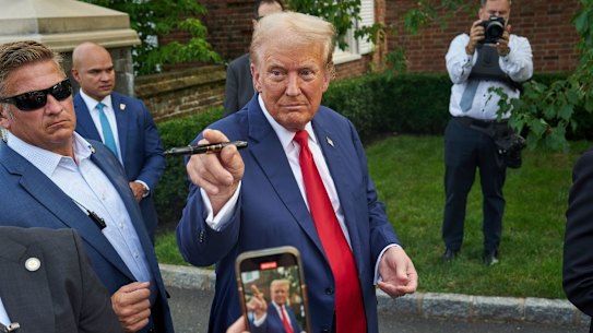 Former US President Donald Trump, center, greets attendees following a news conference at Trump National Golf Club in Bedminster, New Jersey, US, on Thursday, Aug. 15, 2024. The former president’s family business is seeking to build residences and retail inside the Trump National Doral Miami resort, according to documents posted on a City of Doral website. 