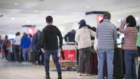 Passengers queue to enter check-in areas for Qantas at Sydney Airport.