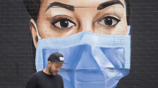 A man passes a mural depicting a nurse wearing scrubs and face mask in the Shoreditch area of east London, following the introduction of measures to bring England out of the coronavirus lockdown, Thursday June 4, 2020.  