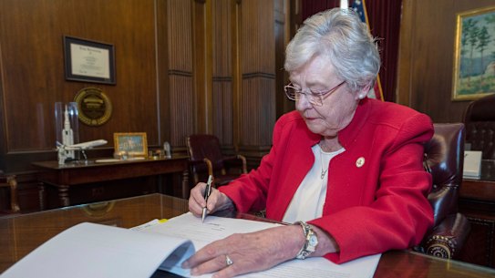 This photograph released by the state shows Alabama Governor Kay Ivey signing a bill that virtually outlaws abortion in the state on Wednesday.