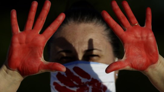 A demonstrator shows her red-painted hands representing the blood of the more than 216,000 deaths from the COVID-19 pandemic in Brazil, during a protest against the government’s response in Brasilia on Sunday.