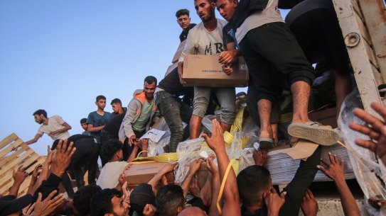 Palestinians distribute food aid that entered the southern Gaza Strip through the UN World Food Program in the Wadi Gaza area on Saturday.