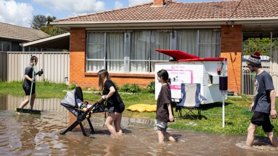 Local residents walk through a flooded street in Shepparton.