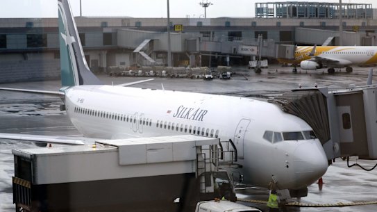 FILE - In this Oct. 4, 2017, file photo, SilkAir's new Boeing 737 Max 8 aircraft is seen through a viewing gallery window parked on the tarmac of Singapore's Changi International Airport. China's civilian aviation authority has ordered all Chinese airlines to temporarily ground their Boeing 737 Max 8 planes after one of the aircraft crashed in Ethiopia. The Civil Aviation Administration of China said the order was issued at 9 a.m. Beijing time Monday, March 11, 2019 and would last nine hours. (AP Photo/Wong Maye-E, File)