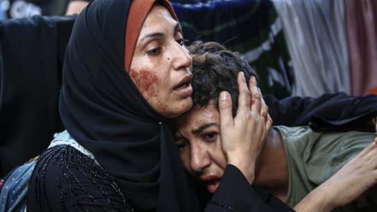 A Palestinian woman consoles a child following Israeli airstrikes on the al-Fakhoora district of Jabalia, northern Gaza on Saturday.