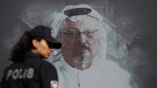A Turkish police officer walks past a picture of slain Saudi journalist Jamal Khashoggi prior to a ceremony, near the Saudi Arabia consulate in Istanbul, marking the one-year anniversary of his death, Wednesday, Oct. 2, 2019. A vigil was held outside the consulate building Wednesday, starting at 1:14 p.m. (1014 GMT) marking the time Khashoggi walked into the building. (AP Photo/Lefteris Pitarakis)