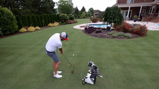 Marc Leishman hits the ball to the green in his backyard while his dog Doc looks on in Virginia Beach. 