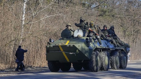 A man pushes a baby stroller as he waves to Ukrainian soldiers on an armoured personnel carrier passing by in the Vyshgorod region close to Kyiv this month. 