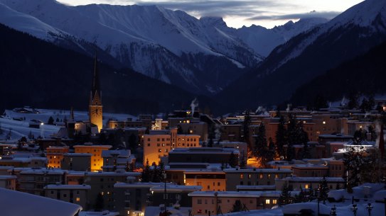 Buildings stand illuminated as dusk falls in Davos.