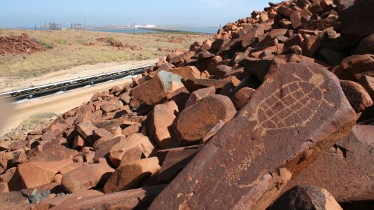 An engraving of a sea turtle on the Burrup Peninsula, Western Australia. The petroglyphs are near industrial complexes, including the Dampier salt stockpiles in the background. 