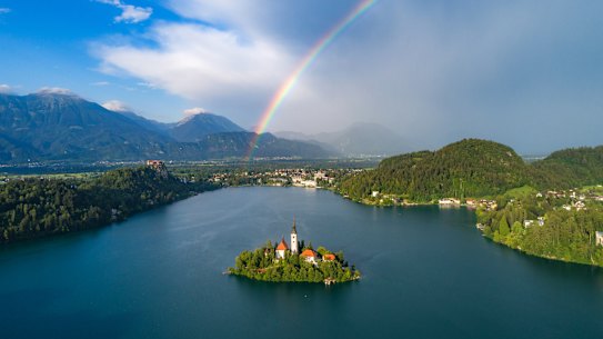 Em algum lugar e um arco-íris: Lago Bled, a ilha e os Alpes.