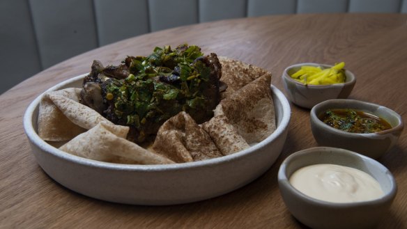 The signature lamb neck shawarma with tarator, pickles and saida saj.