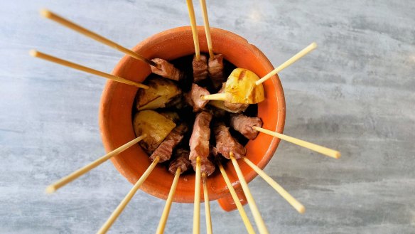 Arrosticini (skewers) served in a traditional terracotta container at Abruzzo Lab.