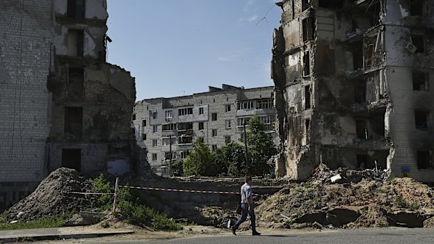 A man walks past the ruins of an apartment building complex destroyed by a Russian missile strike in Borodyanka.