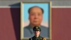 A policeman stands guard near Mao Zedong's portrait on Tiananmen Gate in Beijing. Admirers of Mao have found things to like about the US president.