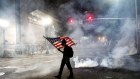 A Black Lives Matter protester carries an American flag as teargas fills the air outside the Mark O. Hatfield United States Courthouse.