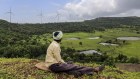 A goat herder sits looking out as wind turbines manufactured by Gamesa Corp. stand at the Bharat Light & Power Ltd. Amberi wind farms in Rewalkawadi, Maharashtra, India, on Tuesday, Sept. 9, 2014. Prime Minister Narendra Modi's government in July restored a wind-farm tax benefit, which could propel wind installations to a three-year high of 2,600 megawatts in 2014, according to Bloomberg New Energy Finance. Photographer: Dhiraj Singh/Bloomberg