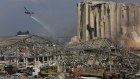 A helicopter drops water on smoldering buildings in the city's port, destroyed by Tuesday's explosion.