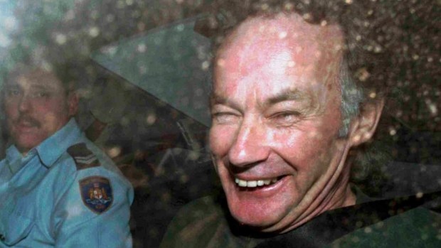 FILE - In this Nov. 4, 1997, file photo, Ivan Milat smiles in a police car after attending a court in Sydney, Australia. Milat, whose grisly serial killings of young backpackers horrified Australians in the early '90s, died in a Sydney prison on Sunday, Oct. 27, 2019, prison authorities said. He was 74. (AP Photo/Rick Rycroft, File)