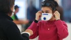 SYDNEY, AUSTRALIA - MARCH 16: A passenger at Sydney airport covers her face with a mask on March 16, 2020 in Sydney, Australia. Strict new border measures to contain the spread of COVID-19 have come into effect Monday, requiring all overseas arrivals to Australia to self-isolate for 14 days. Australia currently has 300 confirmed cases of coronavirus while five people have died  four in NSW and one in Queensland. (Photo by Brendon Thorne/Getty Images)