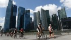 A group of tourists ride their bicycles along the promenade at Marina Bay in Singapore.