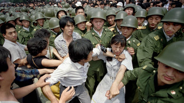 A woman is caught between civilians and Chinese soldiers, who were trying to remove her from an assembly near the Great Hall of the People in Beijing, on June 3, 1989. 