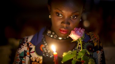 A Kenyan holds a candle and flowers as she listens to the names of each of the victims of the Garissa attack being read out aloud, during a vigil at Uhuru Park in Nairobi,in 2015.