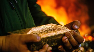 A worker carries a 28 kilogram gold bar after casting and cleaning in the foundry at the South Deep gold mine in South Africa.