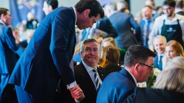 Eddie McGuire, sitting next to Victorian Premier Daniel Andrews, greets Gillon McLachlan on grand final day last year. 