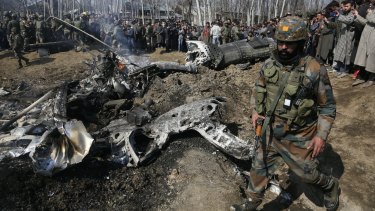 An Indian soldier walks past the wreckage of an Indian aircraft after it crashed in the outskirts of Indian controlled Kashmir.