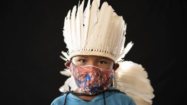 Six-year-old Ezinaldo dos Santosposes wears the traditional dress of his tribe and a Spiderman face mask in the Gaviao community near Manaus, Brazil, on Friday.