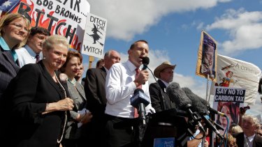 Then opposition leader Tony Abbott in front of a "ditch the witch" poster at a rally outside Parliament House in 2011.