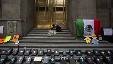 An activist against abortion places an image of Our Lady of Guadalupe alongside small, mock coffins at the entrance to the Supreme Court to protest a ruling on abortion in 2020.