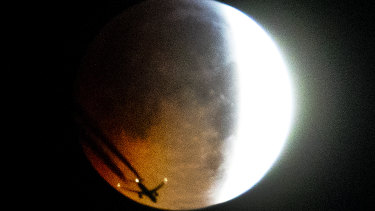 An aircraft flies across the face of the full moon as the lunar eclipse begins in Frankfurt early on Monday.