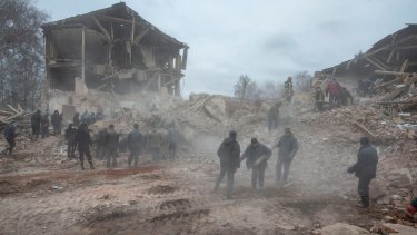People remove debris at the site of a military base building that, according to the Ukrainian ground forces, was destroyed by an air strike, in the town of Okhtyrka in the Sumy region.