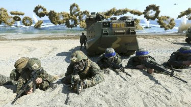 In this March 2016 photo, marines of the US, left, and South Korea, wearing blue headbands on their helmets, take positions after landing on a beach during the a joint military exercise.