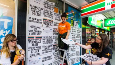 Protestors pin signs to the windows of a 7-Eleven store to protest about the company's worker exploitation and wage fraud scandal.  