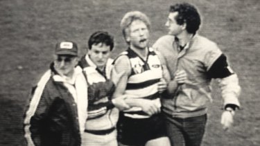 A distressed Neville Bruns is helped from the field in 1985.