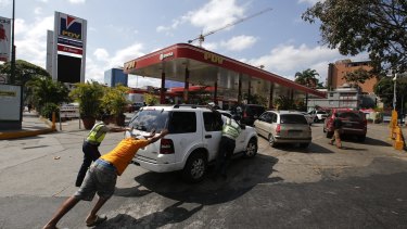 People push a car  to one of the few petrol stations that has its own generator during the blackout in Caracas, Venezuela, on Sunday.