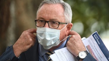 Health Minister Brad Hazzard dons a mask at a coronavirus briefing. 
